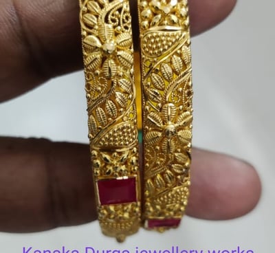 a pair of gold plated bangles with emerald stones