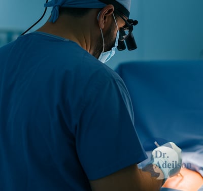 Dr. Adeilson Moreira operando tireoide com lupas cirúrgicas em centro cirúrgico iluminado