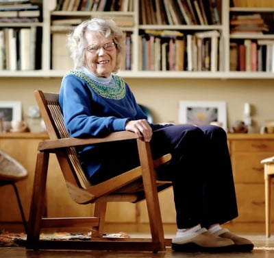 Naoma Powell, one of our founders, sitting in a chair she made, smiling at the camera.