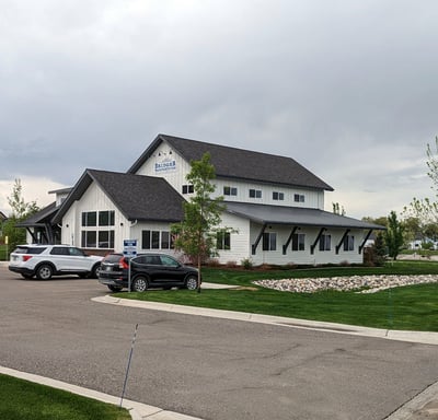 a white house with a black roof and a white car parked in front of it