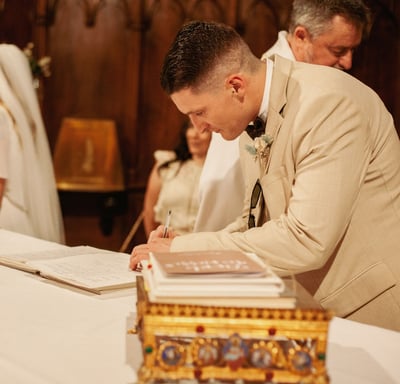 photo aux ton chalereux d'un témoin signant le registre lors du mariage