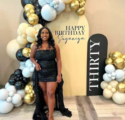 a woman in a black dress standing in front of a birthday sign