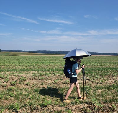 Woman hiking with an umbrella through field
