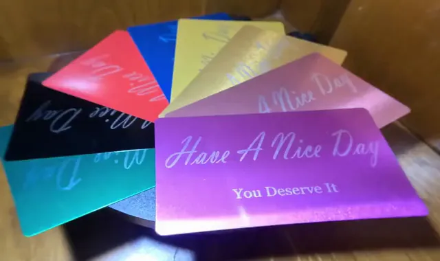 Image d'une variété de couleurs de cartes en métal avec « Passez Une Belle Journée » gravé au laser