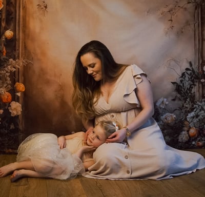 a woman in a white dress is holding a child for mother's day photos