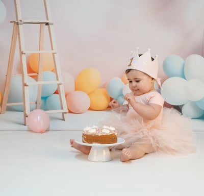 a baby girl in a pink tutu having her first birthday cake smash