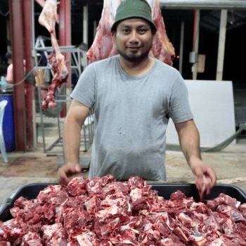 a man standing in front of a large pile of meat