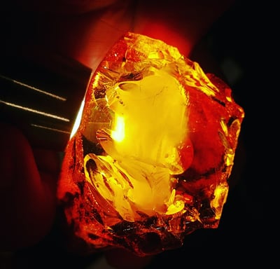 a person holding a piece of amber with a yellow light