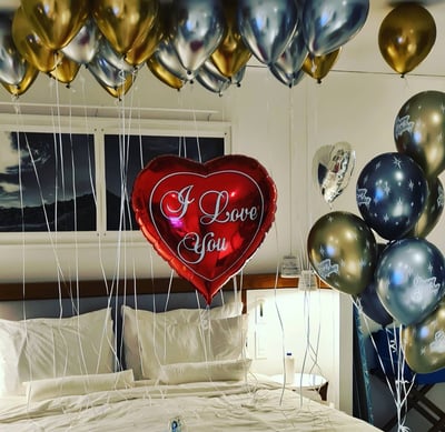 Romantic surprise room setup with heart-shaped balloons for an anniversary celebration.