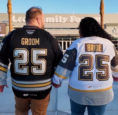 a man and woman holding hands and wearing matching hockey jerseys