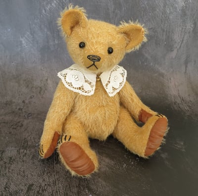 a handmade teddy bear wearing a lace collar