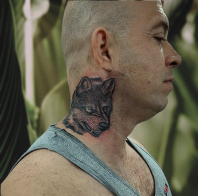 a man with a wolf tattoo on his neck