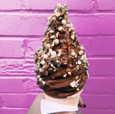 une glace a l'italienne trempée dans du chocolat fondant avec des éclats de cacahuètes 
