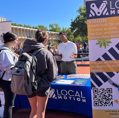 Local Motion table with a staff member talking to the public