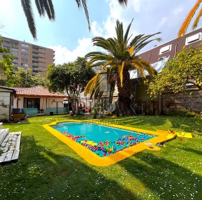 casa con piscina y gran patio verde incluye palmeras y arboles diversos además de un cierre ladrillo