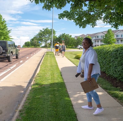 Full-body shot of Sophia Smith walking down a sidewalk with a clipboard in hand