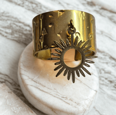 a gold cuff bracelet with a sunflower on it