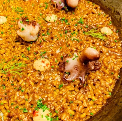 a pan of food with rice paella and octopus tentacles