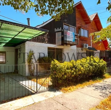 casa dividida color café con reja baja de acero y arbustos , estacionamiento tipo quincho