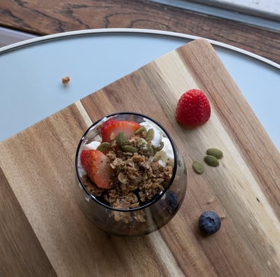 a cup of parfait with yogurt, granola, pumpkin seeds and berries