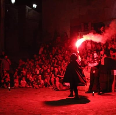 un uomo con mantello nero che inizia lo spettacolo firestorm con un fumogeno rosso