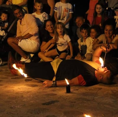un artista steso per terra che mette in scena tecniche di fachirismo e mangiafuoco