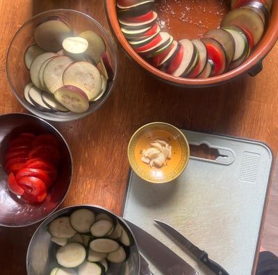 a table with bowls of sliced vegetables and a knife