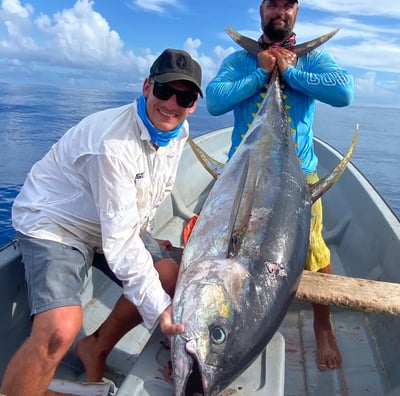 Two men are holding a big Yellowfin Tuna on a boat during a Zanzibar fishing charter