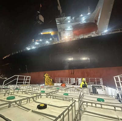 a large ship in the water with a man standing on the deck