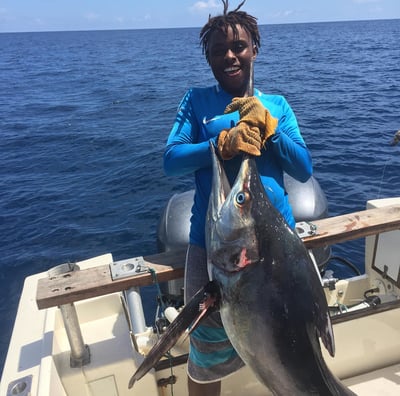 a man holding a fish on a boat