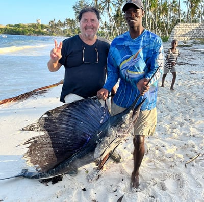 a man holding a fish on a beach