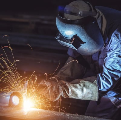 a man in a welding helmet welding a piece of metal