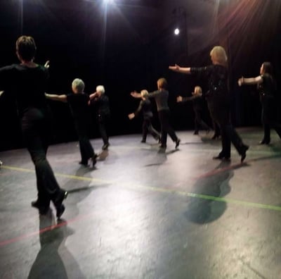 a group of adults tap dancing in a recital in a dance pose