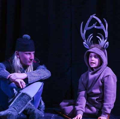 Two youth actors in costumes on stage performing Frozen Jr.