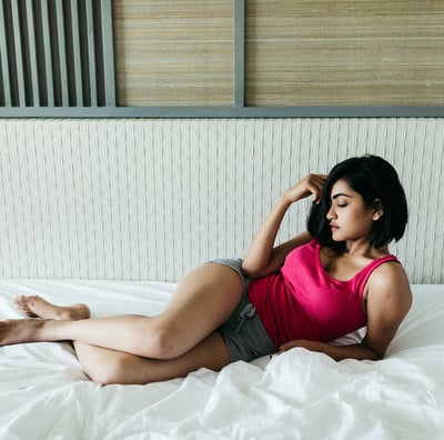 a woman in a pink tank top laying on a bed