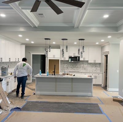 a man standing in a kitchen with a fan and ceiling fan