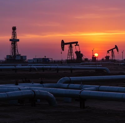 a sunset over a large oil rig with oil pumps