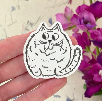 a person holding a sticker with a cat