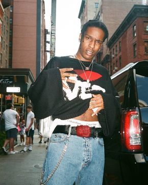 a man in a black shirt and jeans standing on a city street