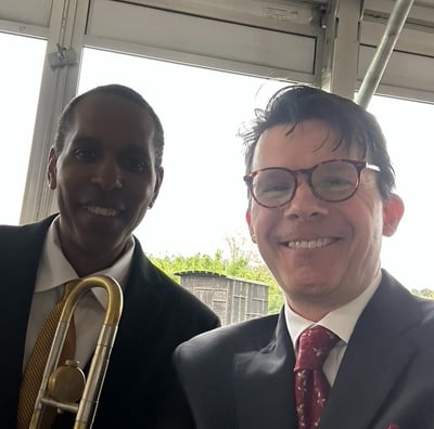Trombonist Vincent Gardner and trumpeter George Chase smile for the camera at a performance.