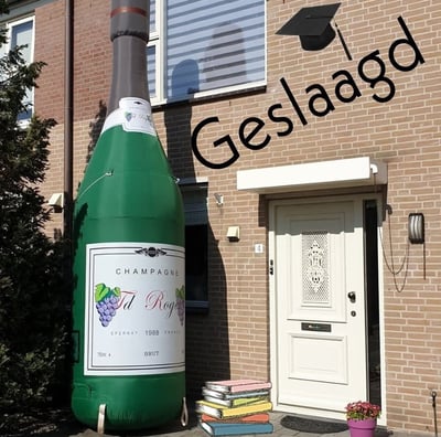 Groene opblaasbare champagne fles aan de voorkant van een huis voor een geslaagde
