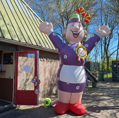 Opblaaspop Sarah, Feestelijke muts op aan de voorkant van een restaurant. Gekleed in Paarse jurk