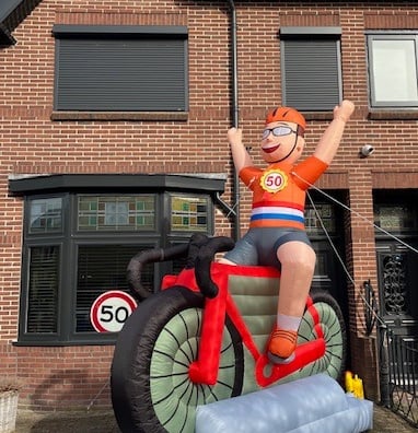 Oblaasbare wielrenner met oranje shirt en Nederlandse vlag zitten op een rode racefiets