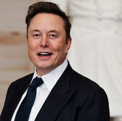 Elon Musk de terno e gravata sorrindo 