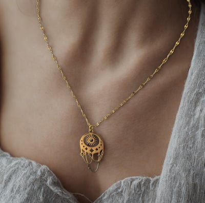 a woman wearing a necklace with a gold chain and a necklace with a heart shaped