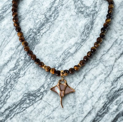 a necklace with a small bird on a marble surface