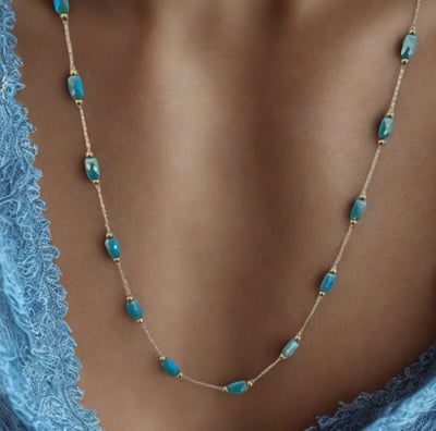 a woman wearing a blue dress and a necklace with a turquoise beaded necklace
