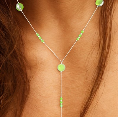 a woman wearing a necklace with green beads and a necklace