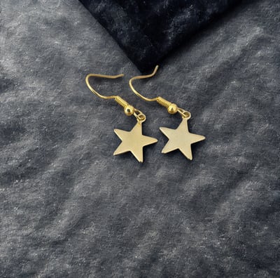 a pair of gold star earrings with a black velvet pouch