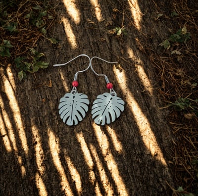 a pair of earrings with a leafy design
